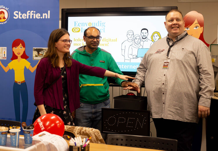 Evelien, Jaspal en Martien drukken samen op de grote rode knop om het project te starten.