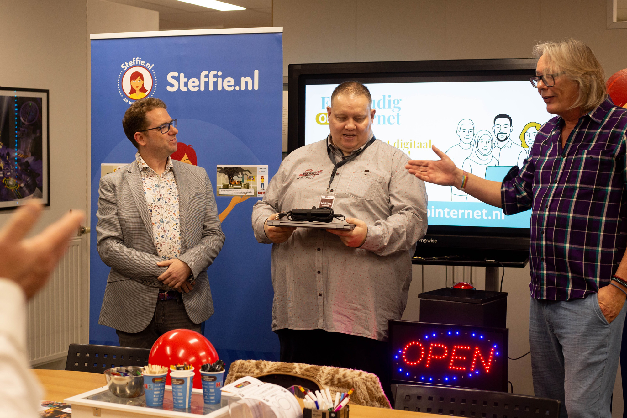 Vrijwilliger Martien kreeg de eerste laptop uitgereikt door Jacques van Leer Zelf Online en Bart van het HomeComputerMuseum.